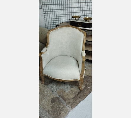 Fauteuil bergère en tissu écru.